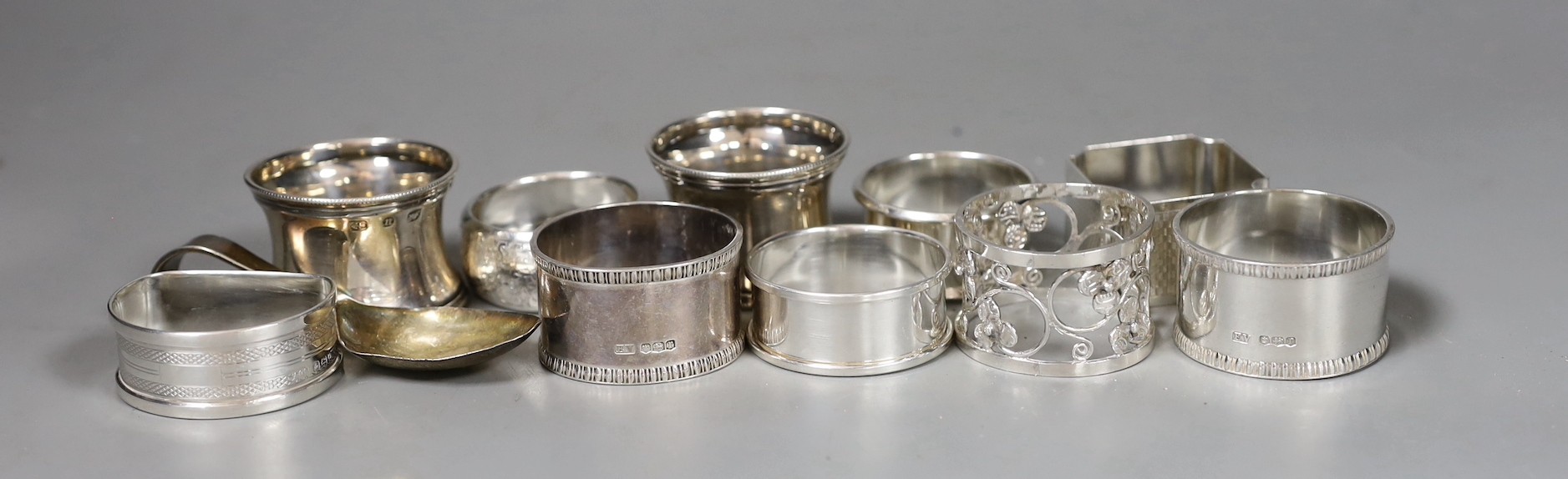 Nine assorted silver napkin rings including a pair of late Victorian and later pair, one other napkin ring and a silver spoon, weighable silver 7oz.